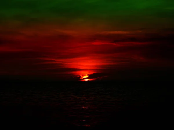 Naplemente utolsó fény, a nap a vízszintes vonal felett sötét zöld égen — Stock Fotó