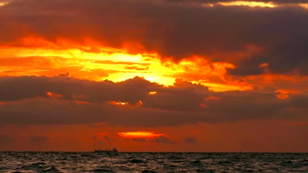 Puesta de sol cielo anaranjado y nube roja oscura que se mueve sobre el mar y pequeña ola de luz solar reflejo de agua — Vídeo de stock