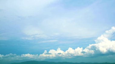 Saf beyaz bulutlu mavi gökyüzü yağmur mevsiminde yeşil tepeyi geçer.