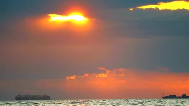 Puesta de sol de nuevo en la nube y los rayos del sol y buque de carga en el mar — Vídeo de stock