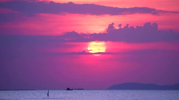 Puesta de sol y nube púrpura en el cielo sobre el mar y la superficie pequeña ola barco de pesca en movimiento pasando — Vídeos de Stock