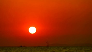 Günbatımı kızıl gökyüzü balıkçı teknesi zaman aşımına uğramış siluet adasını geçiyor