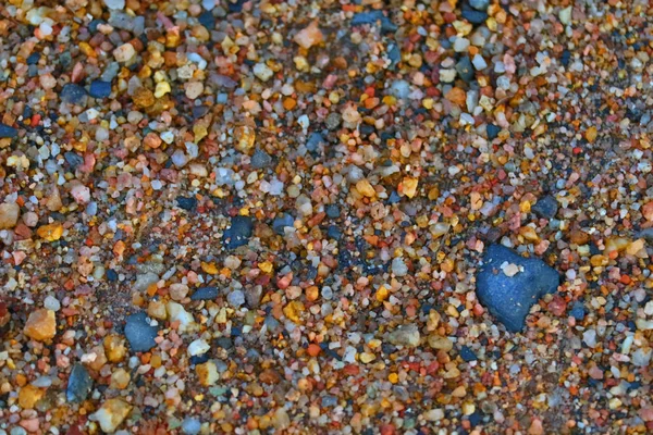 Petites pierres colorées éparpillées sur la plage, causées par eros — Photo