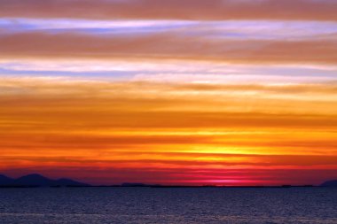 Gökkuşağı ve mavi gökyüzü gün batımında kırmızı turuncu sarı bulut.
