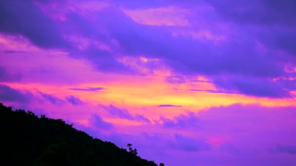 Захід сонця небо з фіолетовим хмарним ходом проходить зелений верхній силует гори — стокове відео