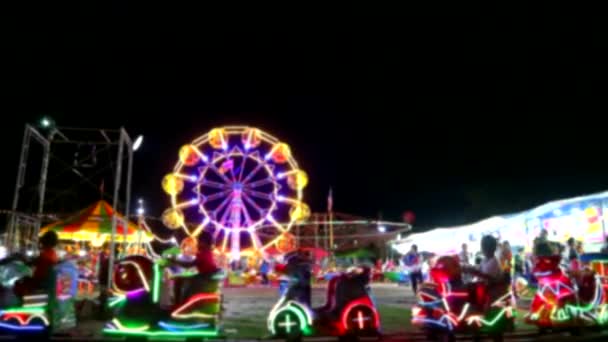 Sfocatura giostra e ruota panoramica e luce al neon del treno nella fiera del mercato notturno 1 — Video Stock