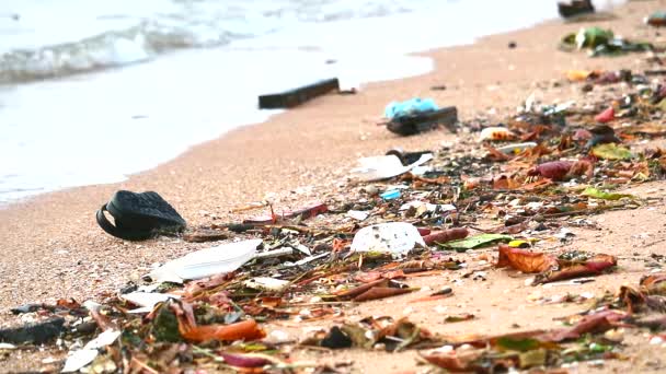 Sonnenuntergang am Strand mit Plastikgummi und Abfall werden am Strand zurückgelassen und von Wellen ins Meer geweht — Stockvideo