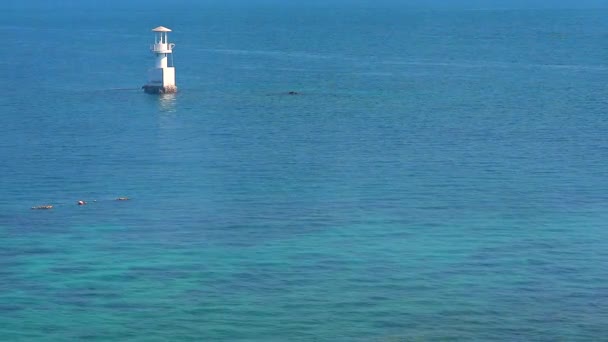 White lighthouse is surrounded by coral reefs in blue green sea — Stock Video