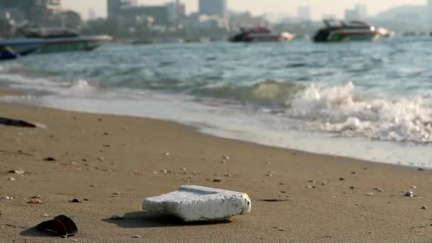 Skum på stranden med plastgummi och avfall lämnas på stranden och vågorna blåste dem i havet — Stockvideo