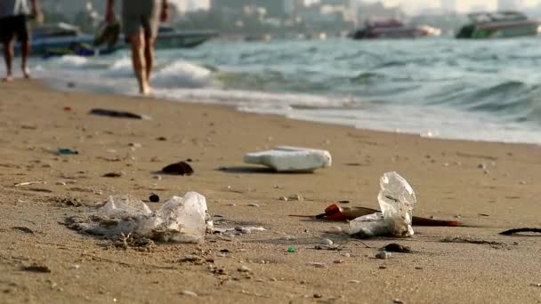 Le persone camminano sulla spiaggia con gomma plastica e rifiuti vengono lasciati sulla spiaggia e le onde li hanno soffiati in mare — Video Stock