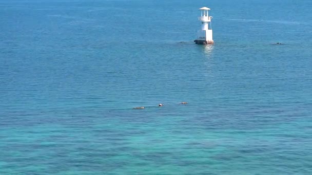 Witte vuurtoren is omgeven door koraalriffen in de blauw groene zee — Stockvideo