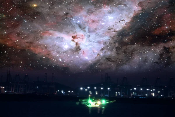 Nebula in galaxy over silhouette seaport  and fishing boat on ni