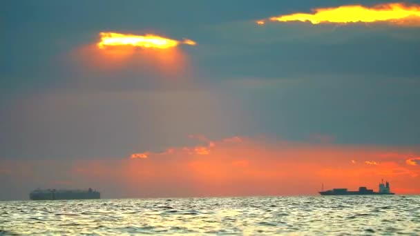 Günbatımı denizde ve kargo gemisi kırmızı turuncu bulutta — Stok video