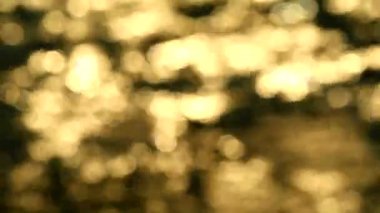 Güneş ışığının bulanık yansıması. Akşam deniz dalgası. Altın sarısı, turuncu ve beyaz Bokeh göz kırpması.