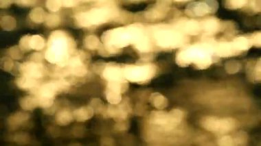 Güneş ışığının bulanık yansıması. Akşam deniz dalgası. Altın sarısı, turuncu ve beyaz Bokeh göz kırpması.