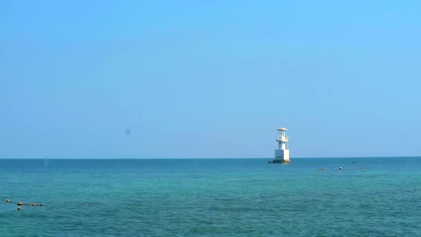 White lighthouse is surrounded by coral reefs in the sea and blue sky — Stock Video