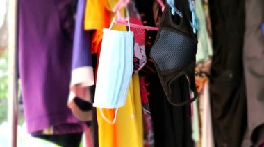 Tek kullanımlık beyaz yüz maskesi ve yıkanabilir siyah renk askıda asılı.