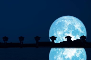 Gece gökyüzündeki Süper Mavi Ay ve Siluet Barajı 'nın yansıması. NASA tarafından desteklenen bu görüntünün elementleri.