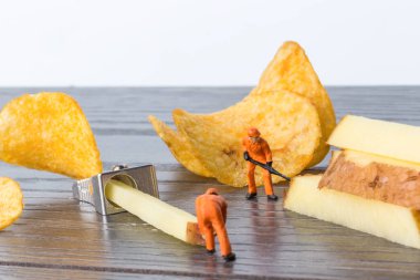 Herhangi bir sorun için toplu bir çözüm kavramı. Minyatür oyuncak işçi Çiğ patates üzerinden yongaları üretmek. Yakın çekim görünümü.