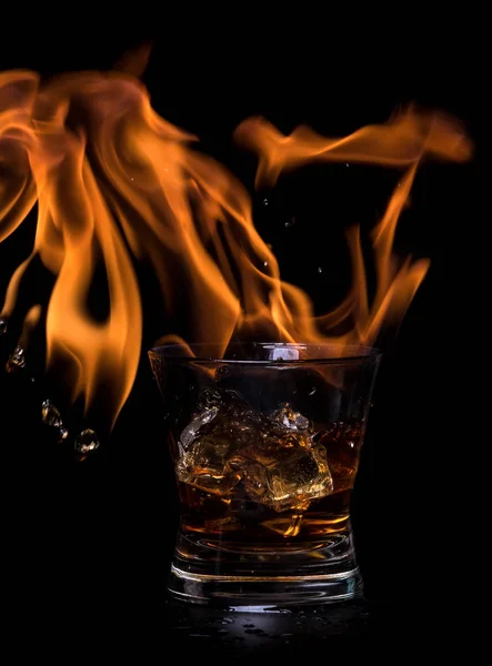 The concept of hot drink with ice cubes in a glass. On a black background. — Stock Photo, Image