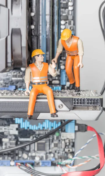 The concept of error correction or repair your computer. Miniature toy engineers fixing error on motherboard. Close-up view.