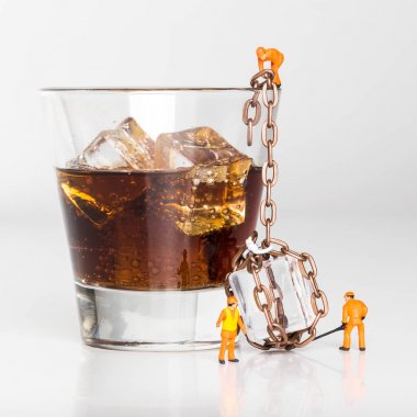 Minyatür insanlar. Alkol bar ve restoranlar kavramı. Minyatür oyuncak işçiler bir buz küpü bir bardak konyak dolu. Yakın çekim görünümü.