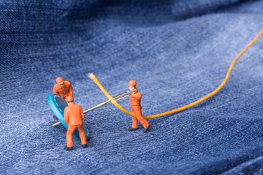 Minyatür insanlar. Moda endüstrisi için kavram. Minyatür işçiler için kot düğmeleri büyük iğne dikmek. Yakın çekim.