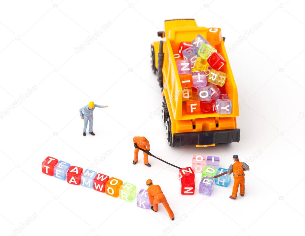 Miniature people. The concept of a collective solution to any problem. Miniature toy workers build the letter 