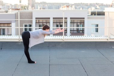 Genç kadın çatıda yoga yaparken