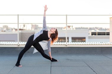 Genç kadın çatıda yoga yaparken