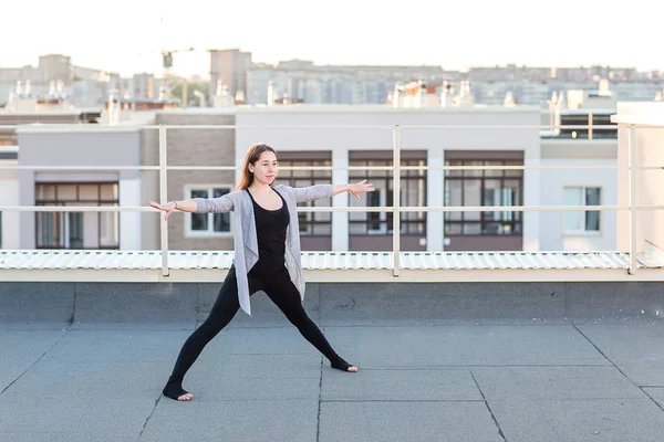 Mujer joven haciendo yoga en el techo — Foto de Stock