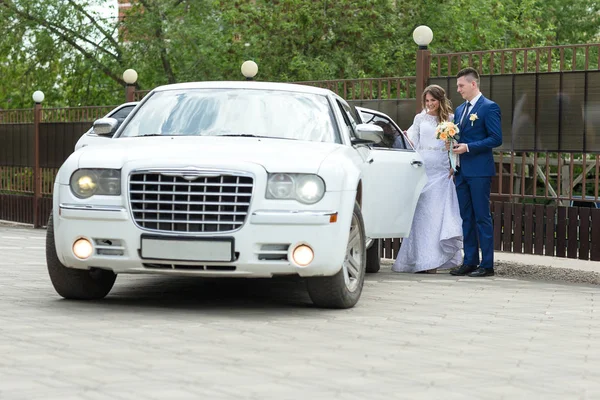 Groom and bride go to car — Stock Photo, Image