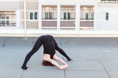 Genç kadın çatıda yoga yaparken