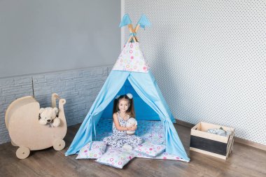 Bir teepee çadır ile oynayan çocuk