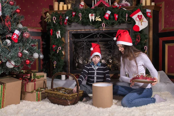 woman gives wrapped christmas presents gifts to son