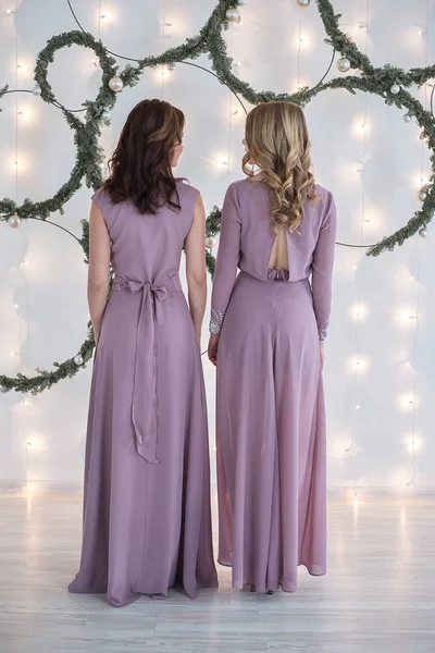 Two woman in dress in front of wall decorated