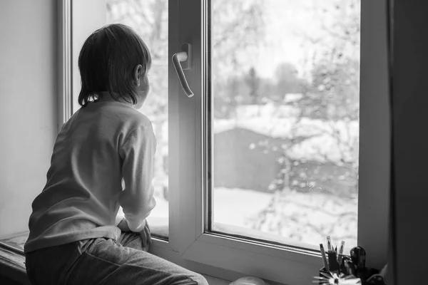 Garçon regarde par la fenêtre un jour d'hiver — Photo