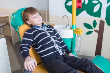 çocuk diş bir sandalyede oturuyor