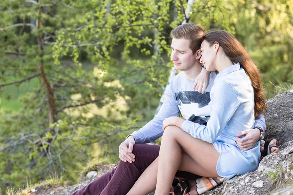 Young couple sitting on the edge of a cliff — Stock Photo, Image