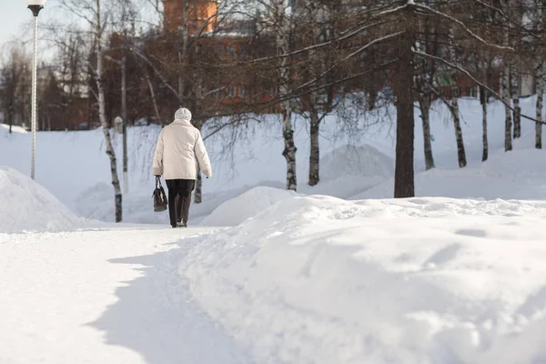 Older woman walking on a snowy road