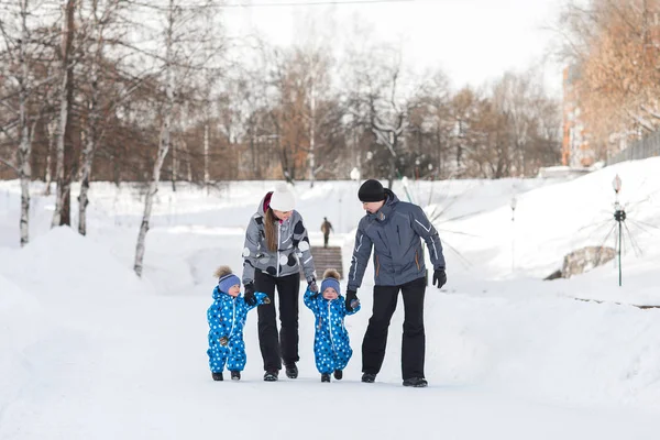 父、母と子供、双子保持する互いの手し、雪の上を歩く — ストック写真