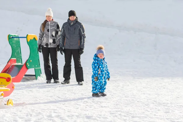 Uma jovem família com um filho caminhando no Parque no inverno em um dia ensolarado — Fotografia de Stock