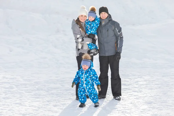 Portrét šťastná rodina s dvojčaty v zimě parku za slunečného dne — Stock fotografie