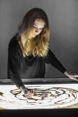 Kadın kum, kum animasyon üzerinde çizer, onun elinden kum dökme