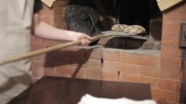 Önlük erkek Baker fırından yeni çıkmış iki somun ekmek alır.