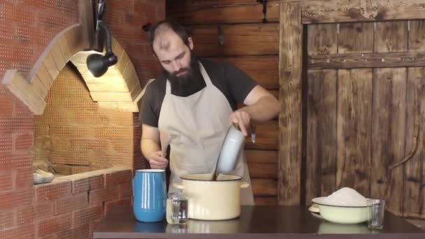 Мужчина пекарь наливает в кастрюлю ингредиенты для смешивания теста — стоковое видео