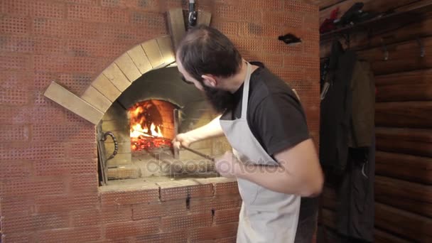 El granjero prepara el horno para cocinar, agita las brasas con el póker — Vídeo de stock