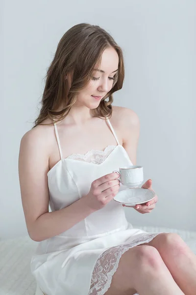 Meisje met kopje koffie in de slaapkamer — Stockfoto