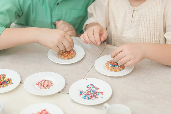 Słodkie dzieci ozdabiają cookies przy stole w kuchni — Zdjęcie stockowe