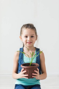 Saksılı bitki tutan şirin çocuk